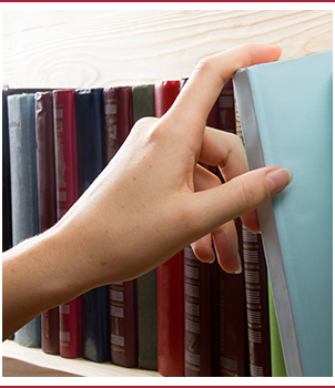 Woman's hand selecting a book from a bookshelf